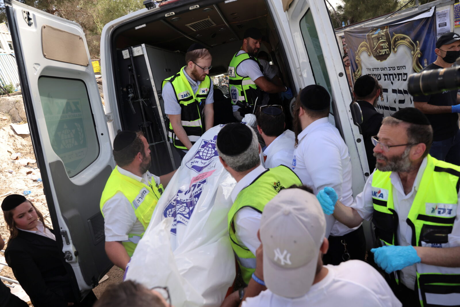Rescue workers take a dead body into an ambulance on Mount Meron