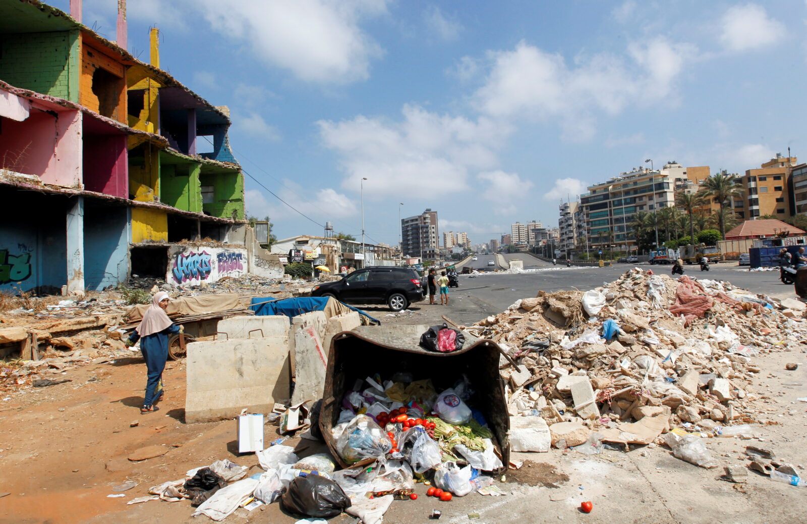 People make their way through a road blocked by protestors as fuel crisis worsens, in Beirut