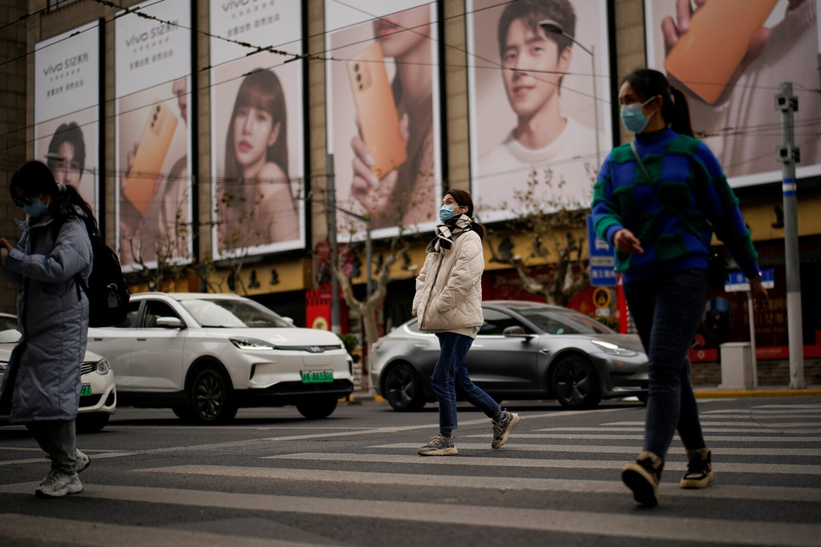 People wearing protective masks walk on a street, following new cases of the coronavirus disease (COVID-19), in Shanghai