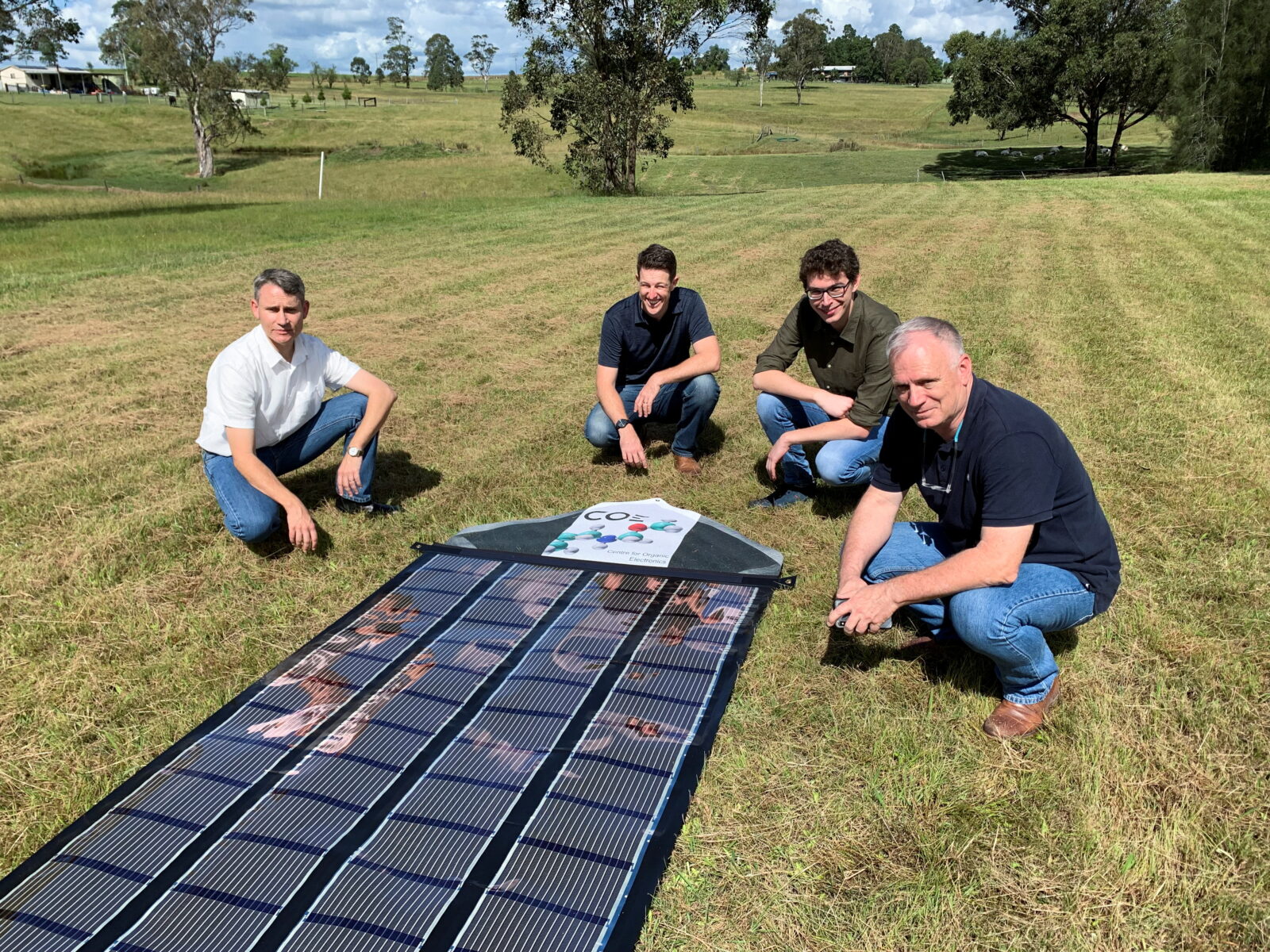 Charge Around Australia project lead and inventor of ‘printed solar’ panels Paul Dastoor and team members next to a printed solar panel, in Gosforth