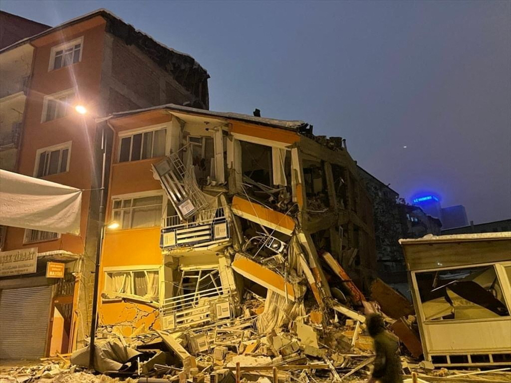 A man walks past by a collapsed building after an earthquake in Malatya