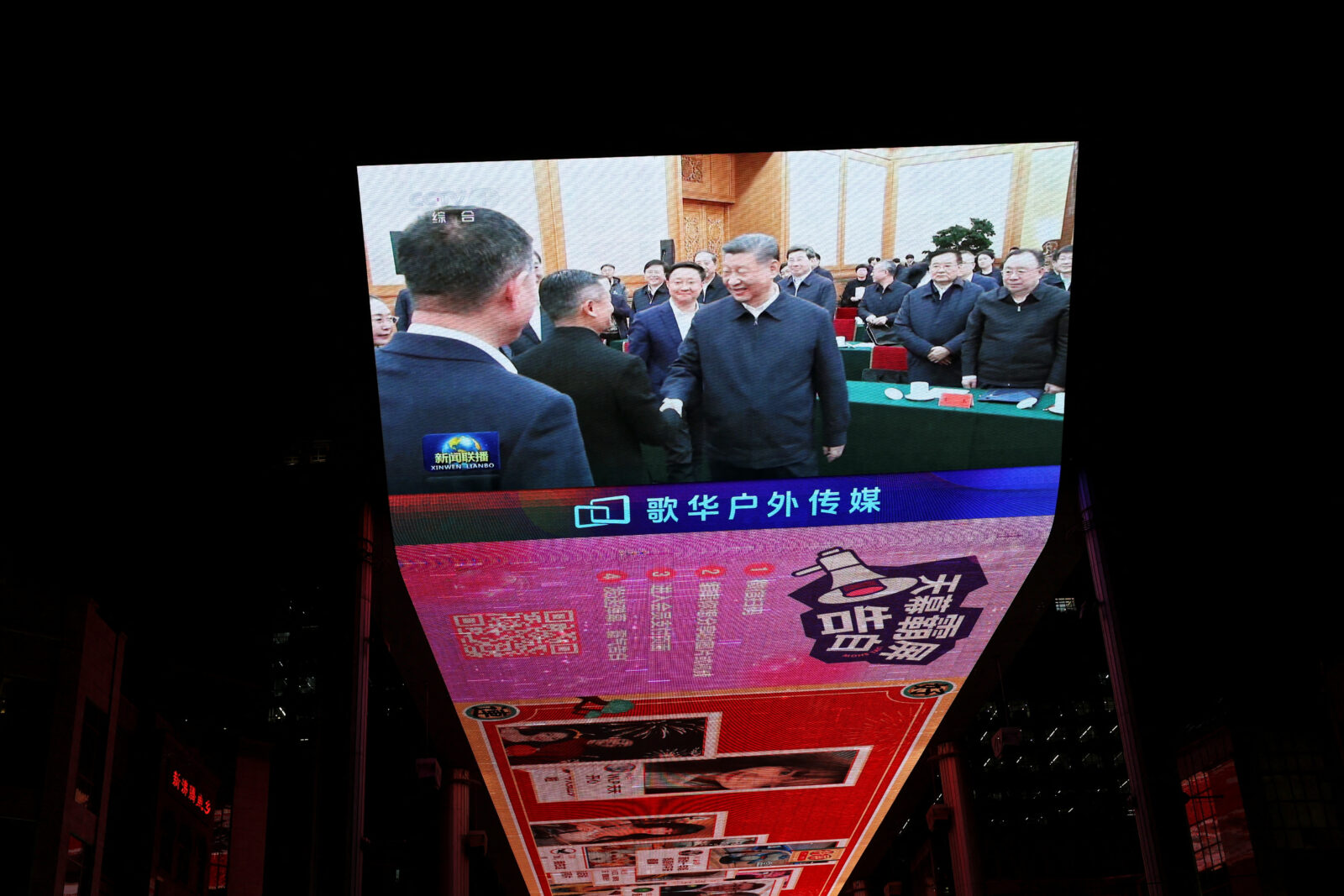 Screen displays news footage of Chinese President Xi Jinping's meeting with business leaders in Beijing